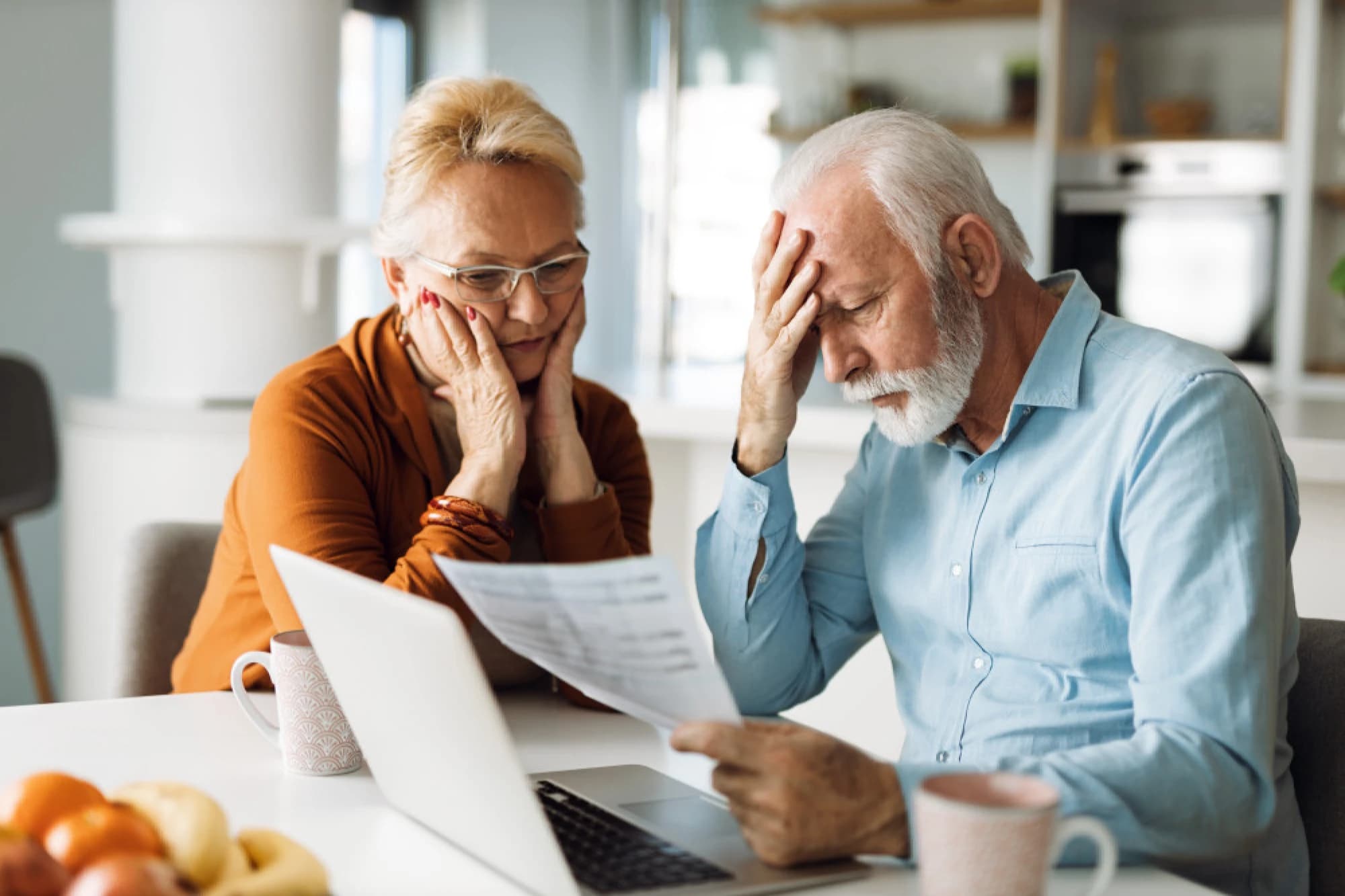 Older couple looking at a laptop, frustrated with their financial advisor.