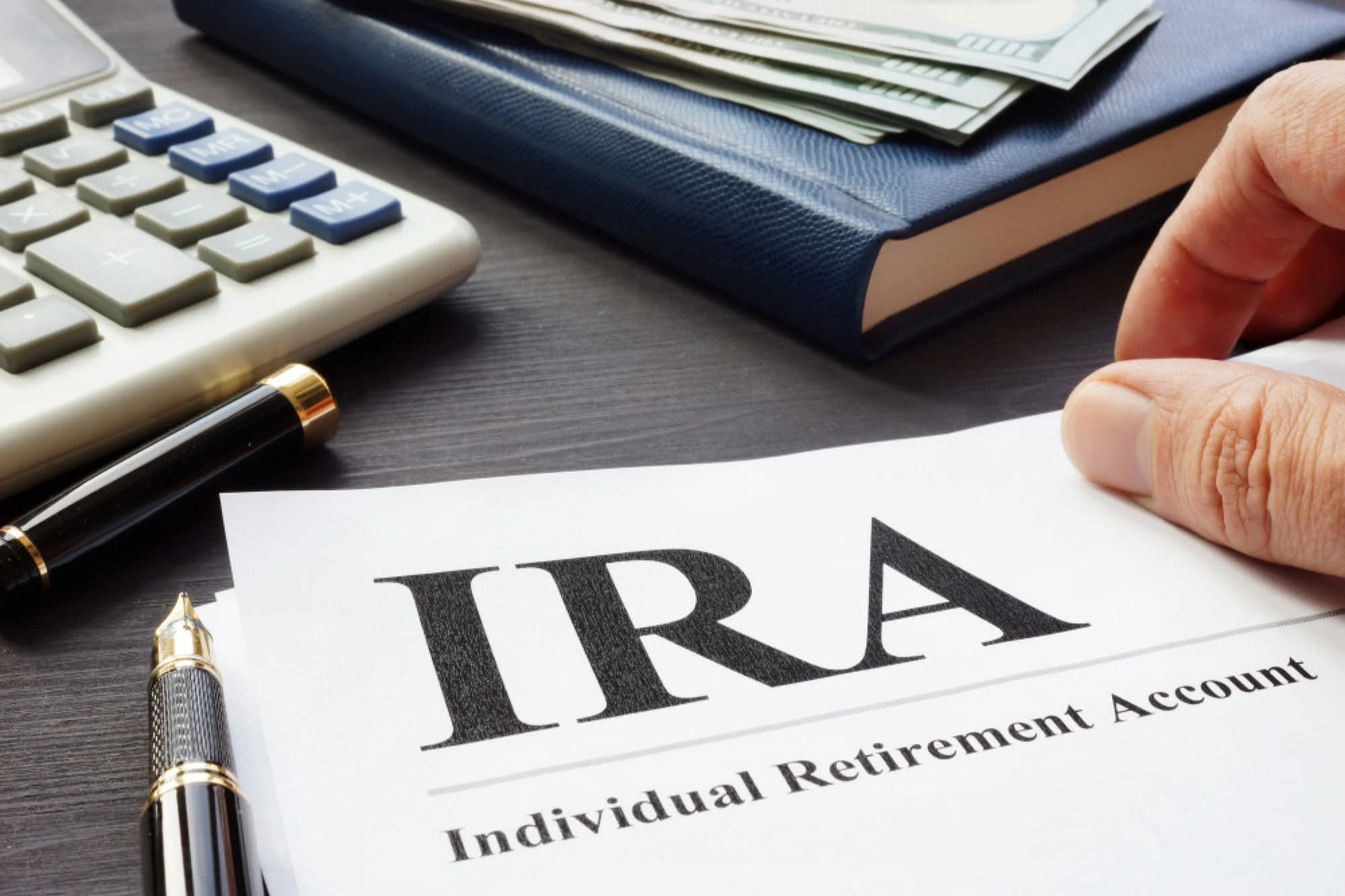 A desk with a calculator, and a form labeled “IRA.”
