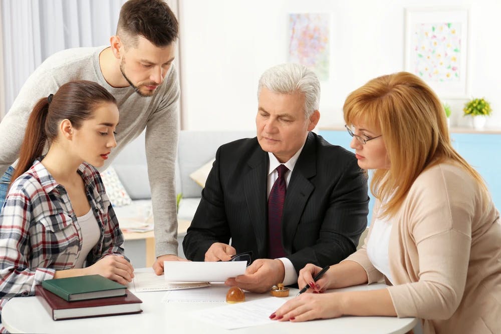 A father and his three adult children reviewing a business document