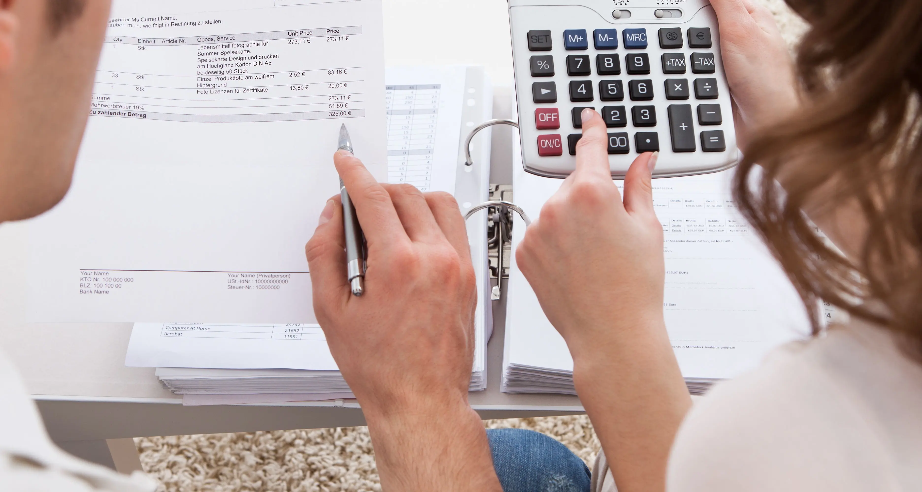 husband and wife using a calculator to review their finances