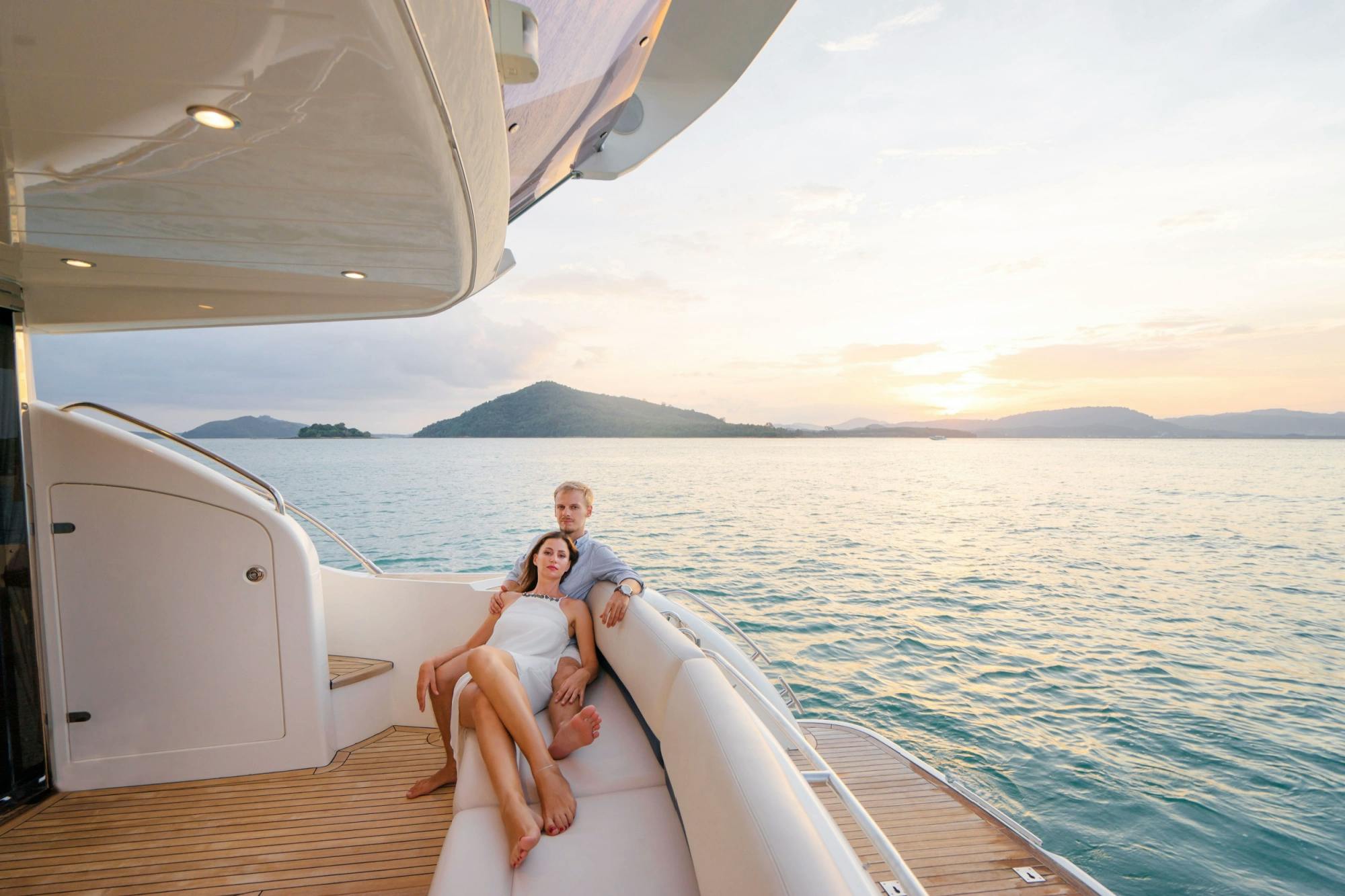 Young couple relaxing on a yacht with mountains in the background.