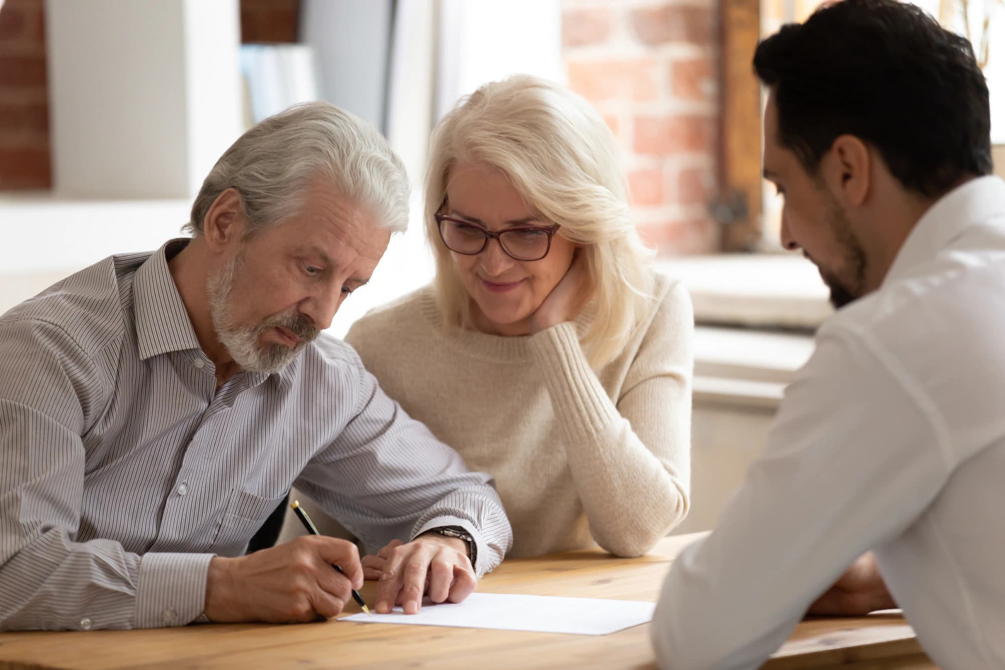 Older couple sign important documents relating to the transfer of their business.