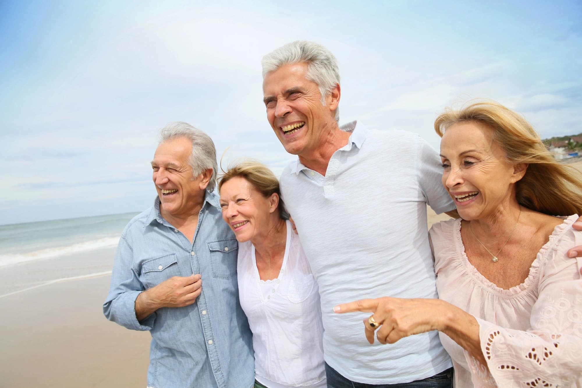 Two retired couples walking on the beach