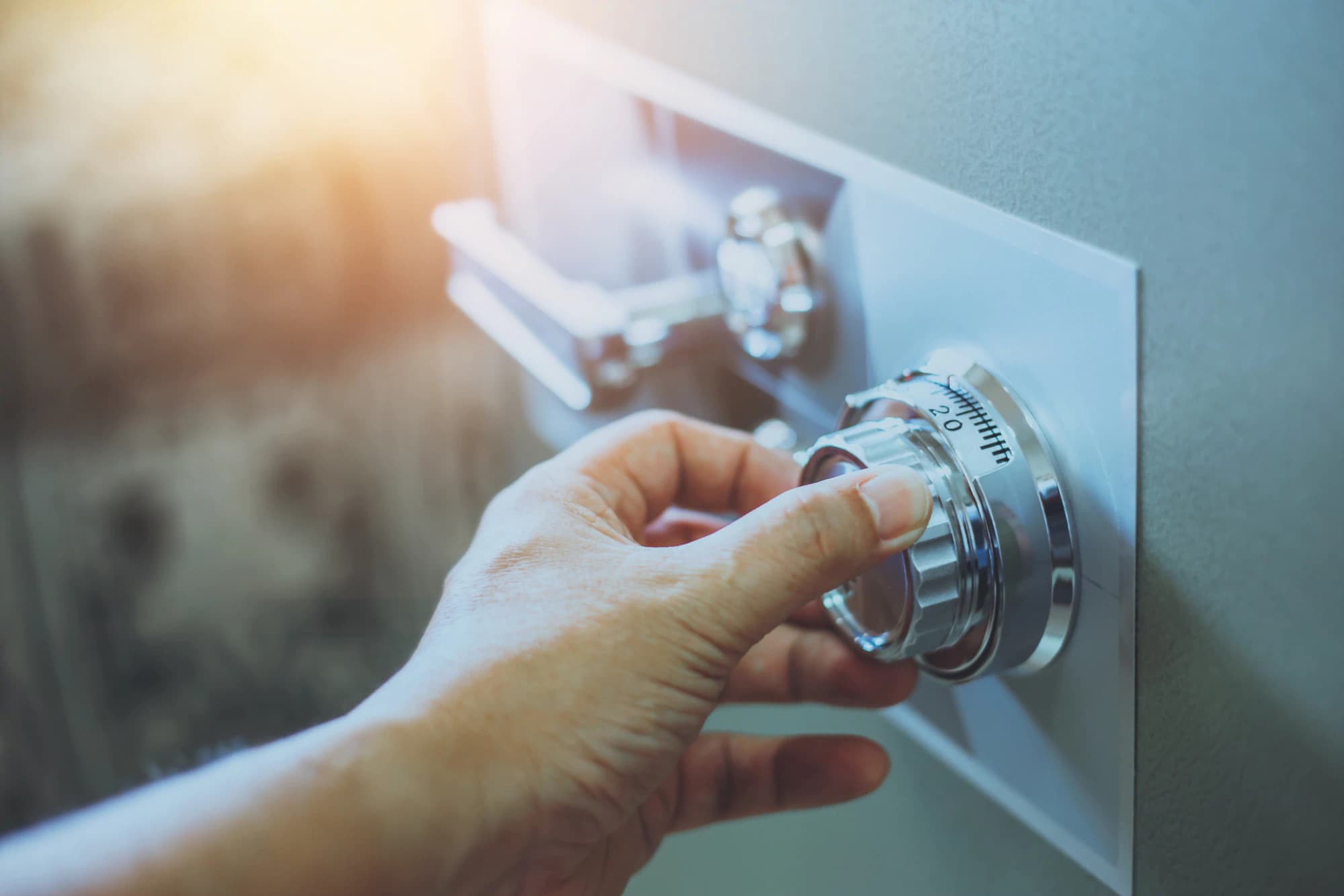 A man’s hand turning the dial on a large safe.