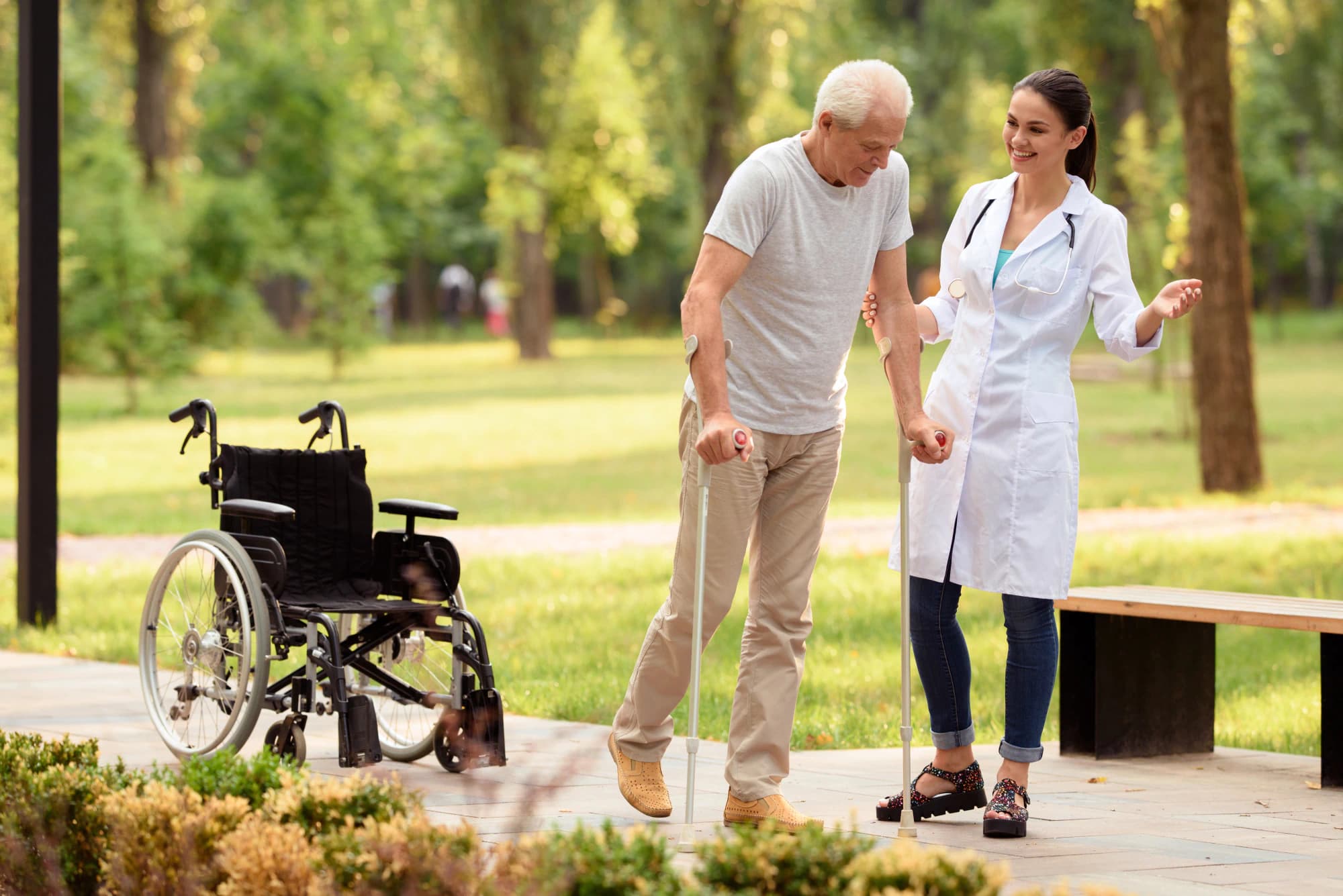 Injured man doing physical therapy in the park with a young doctor.