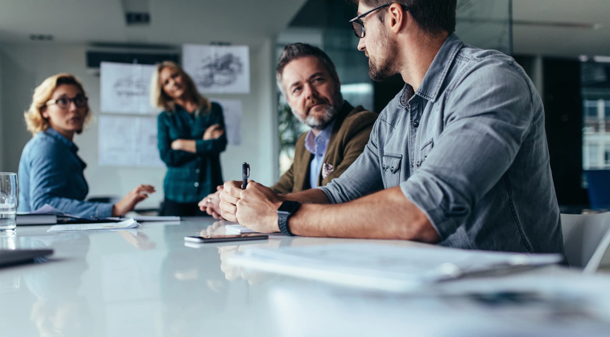 Group of corporate executives discuss financial plans in a modern boardroom.