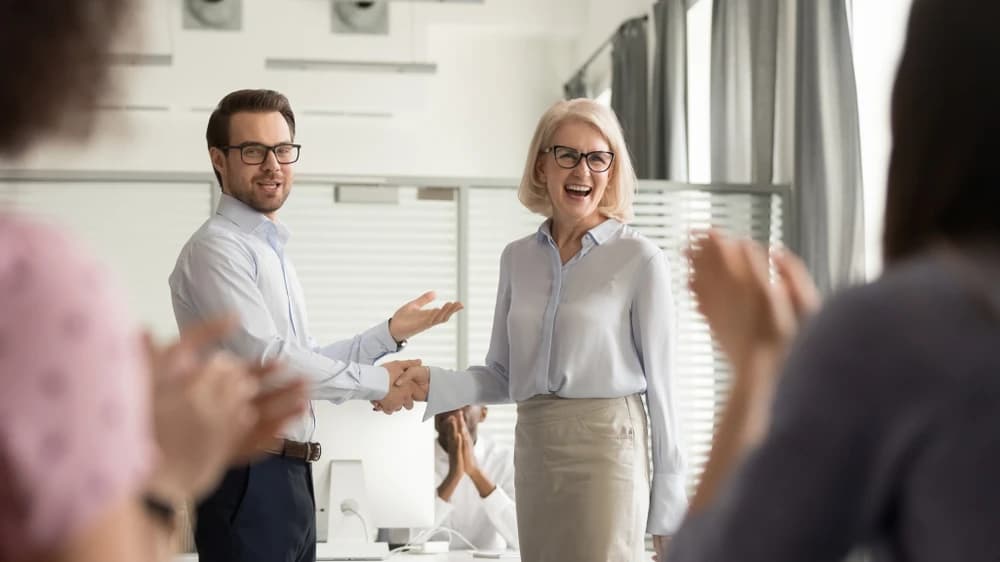 Manager introducing a new executive while employees applaud