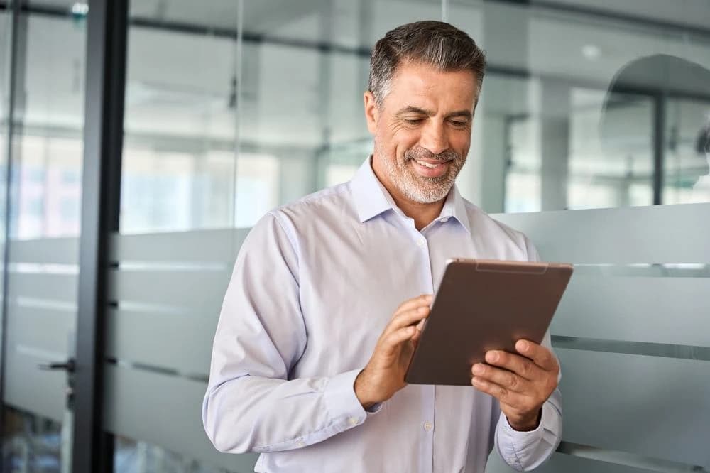 Businessman smiling at his iPad after checking his investment portfolio