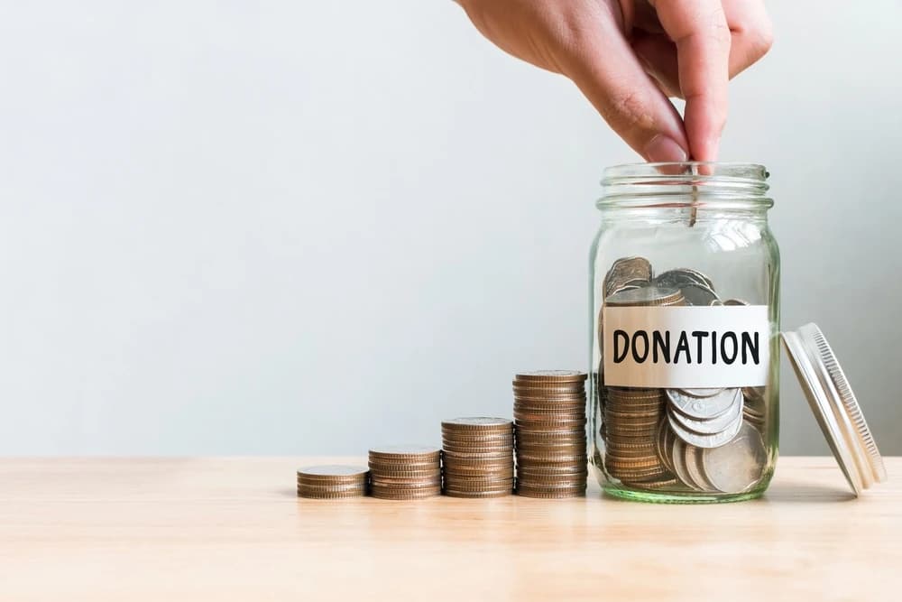 stacks of coins next to a coin jar labeled “Donations”