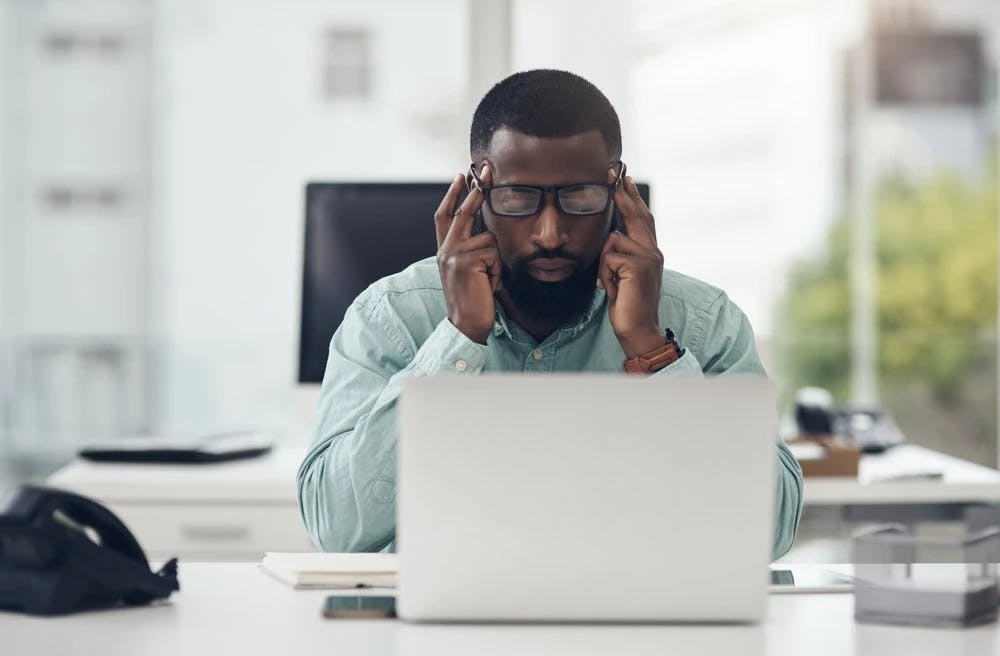 Thinking, stressed businessman on a laptop