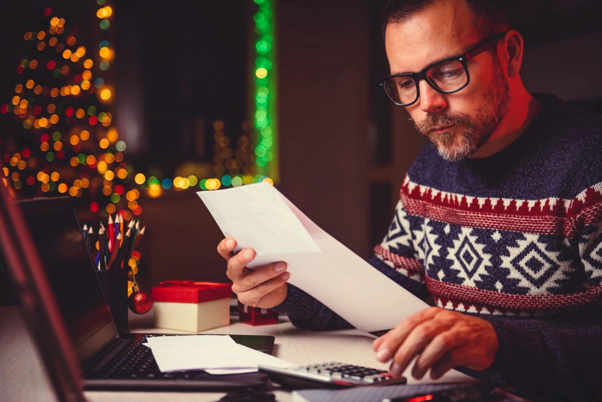 A man in a Christmas Sweater reviewing his end-of-year tax strategy