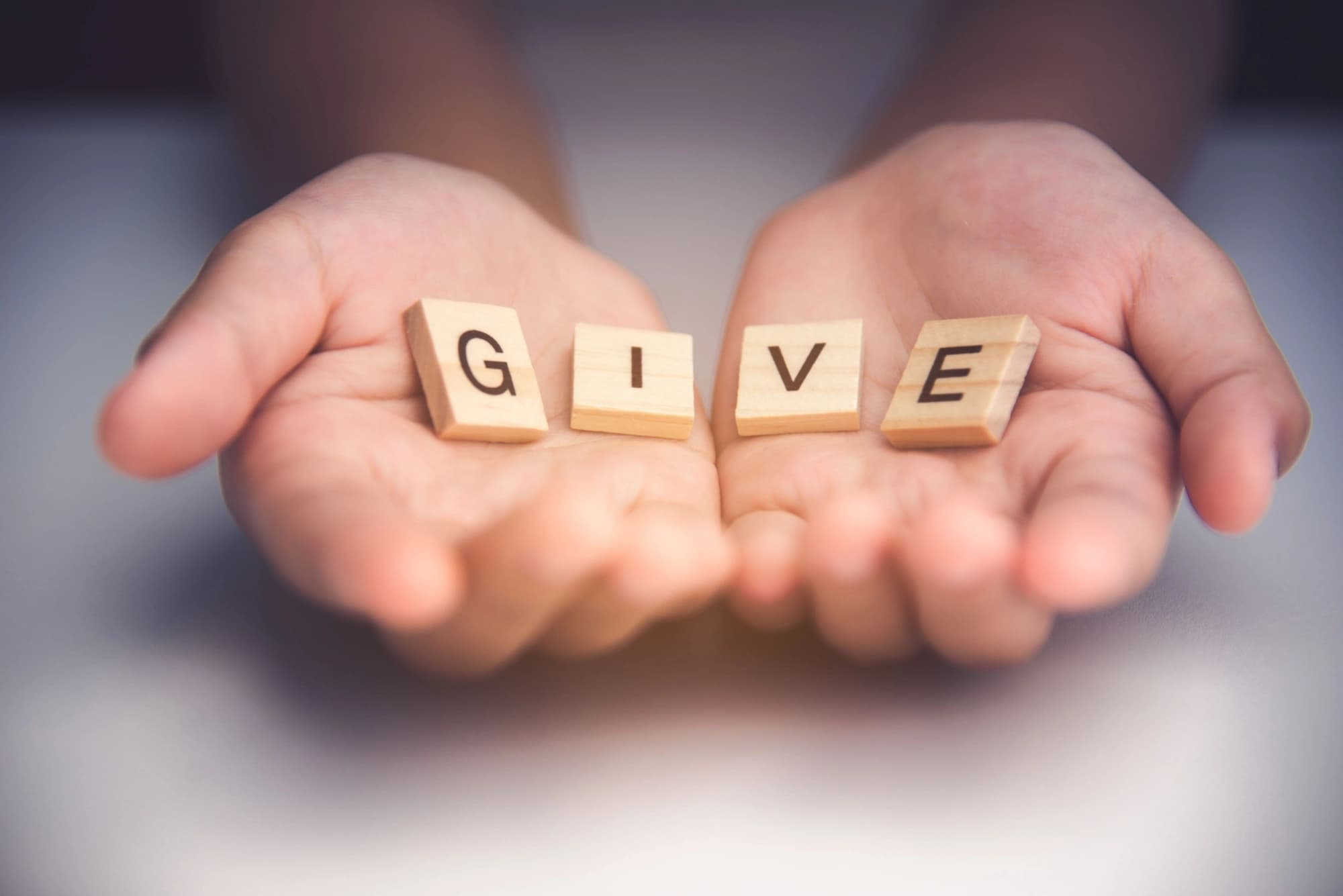 Cupped hands holding letters that spell give