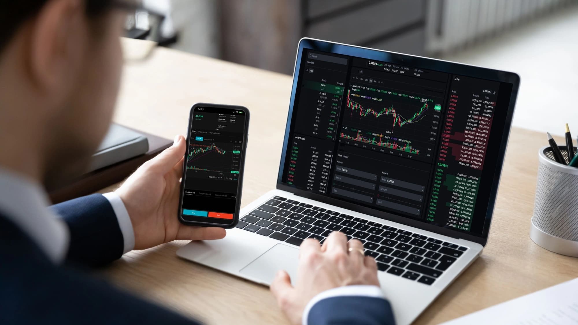 Male trader looking at IPO graphs on his phone and laptop
