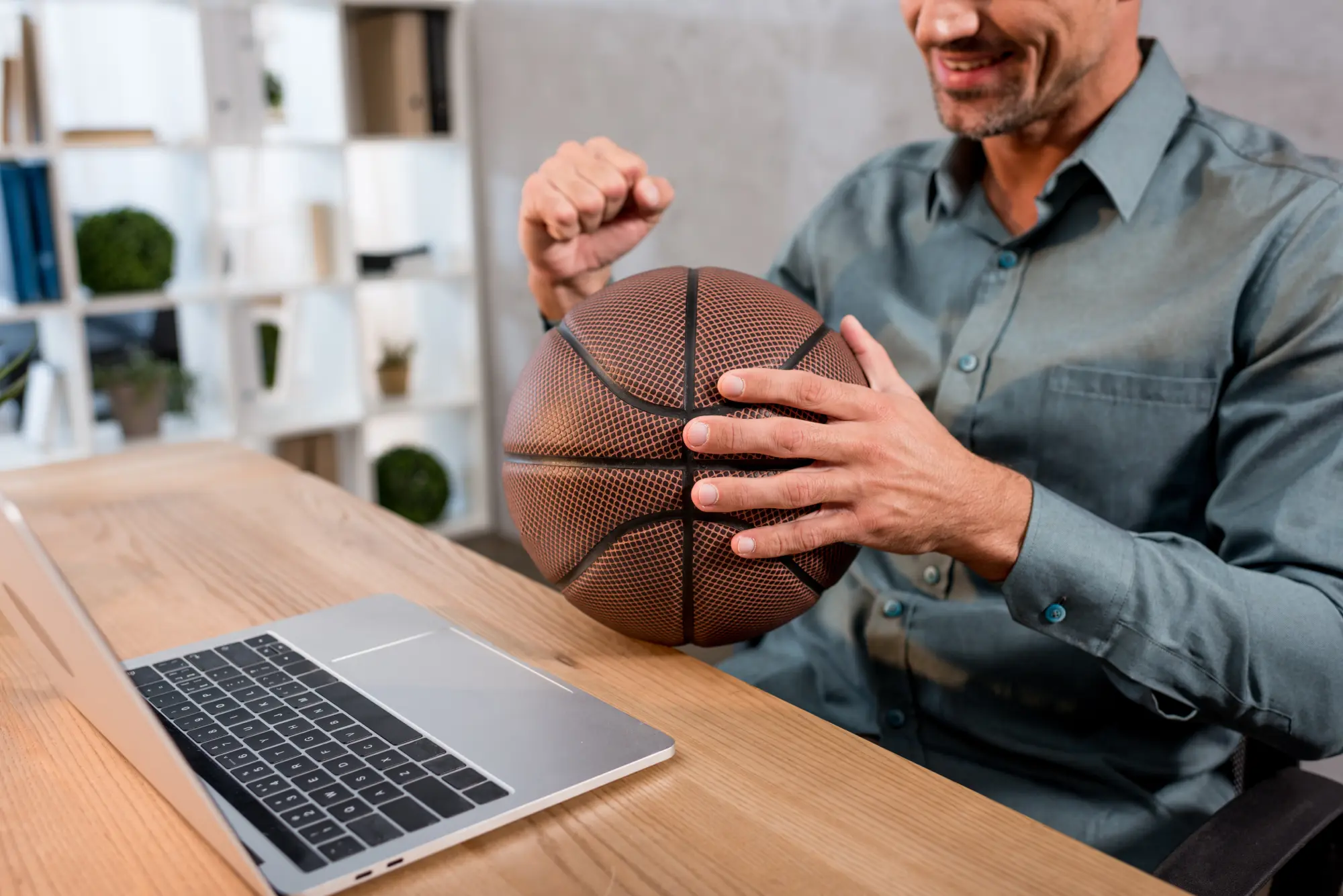 An executive seated at a laptop and holding a basketball