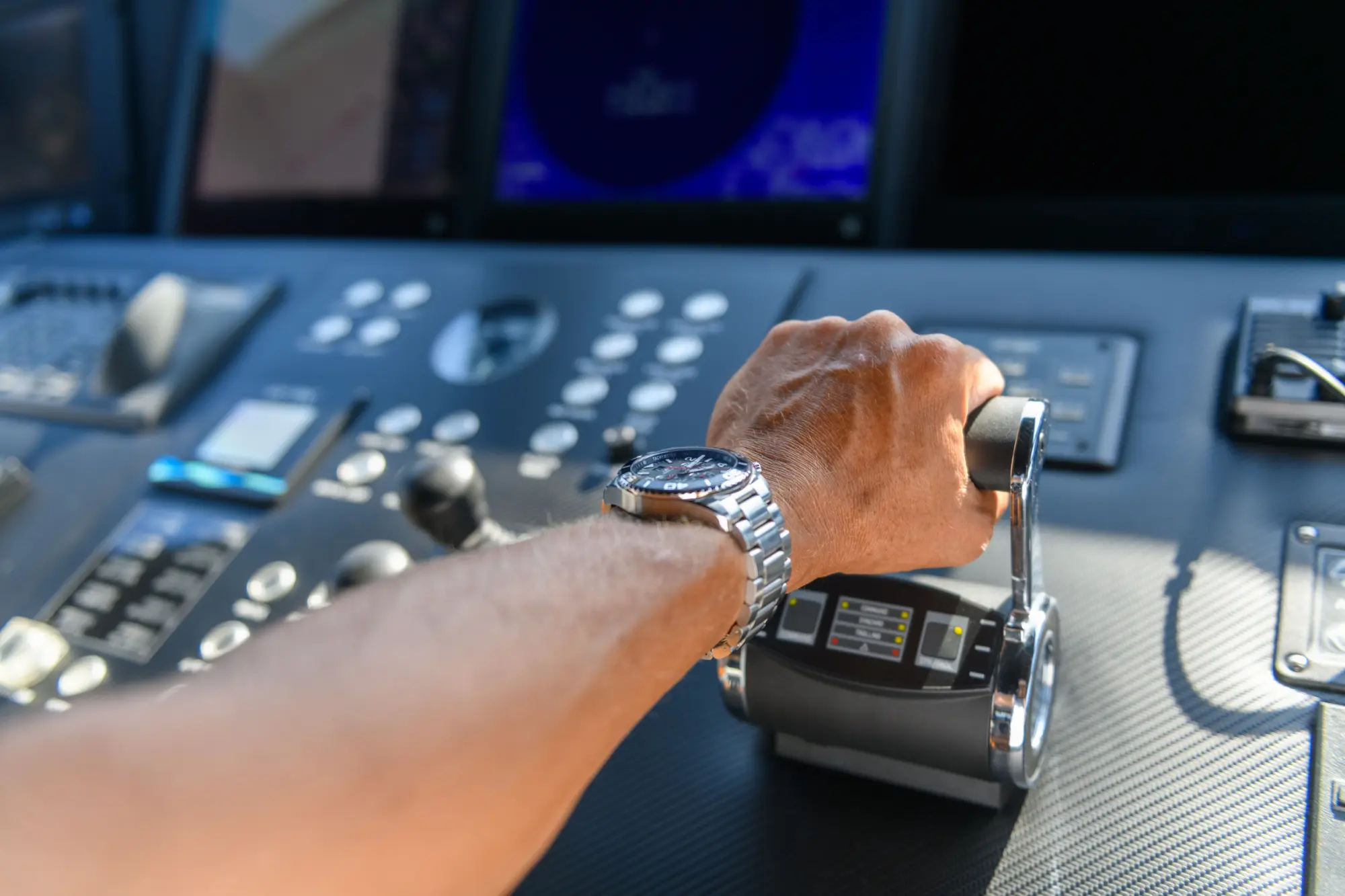 A man's hand at the controls of a yacht