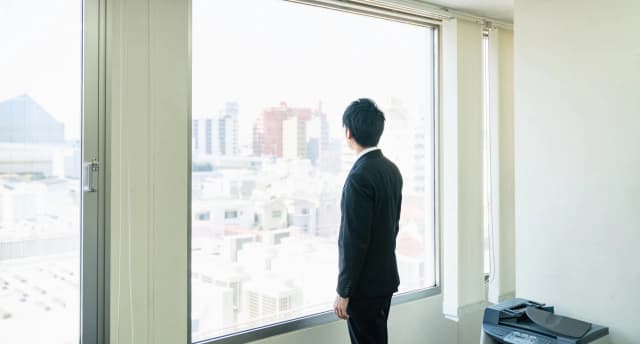 Business man standing at a window in Houston thinking about his business succession plan