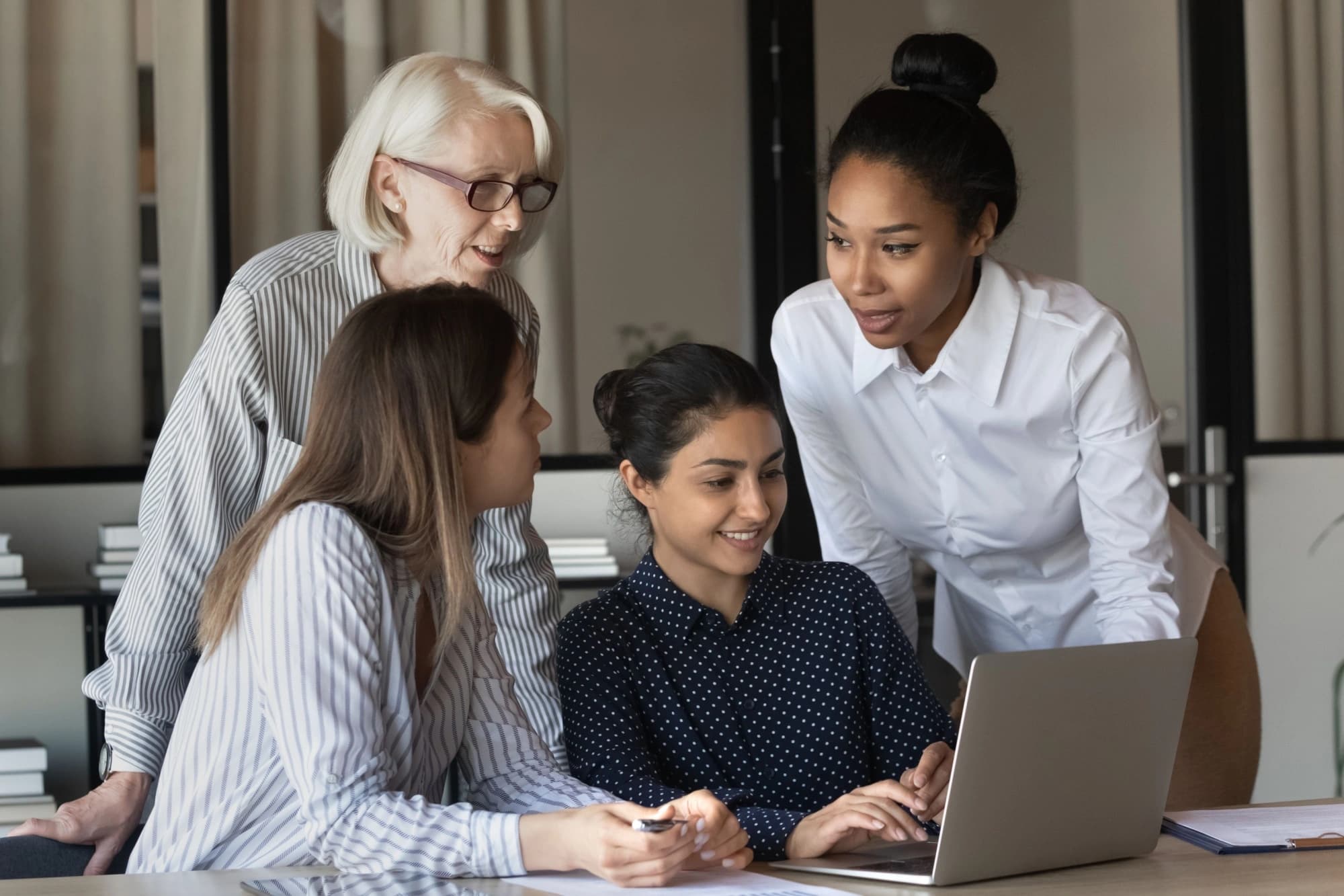 Four female business owners reviewing their financial plan on a laptop