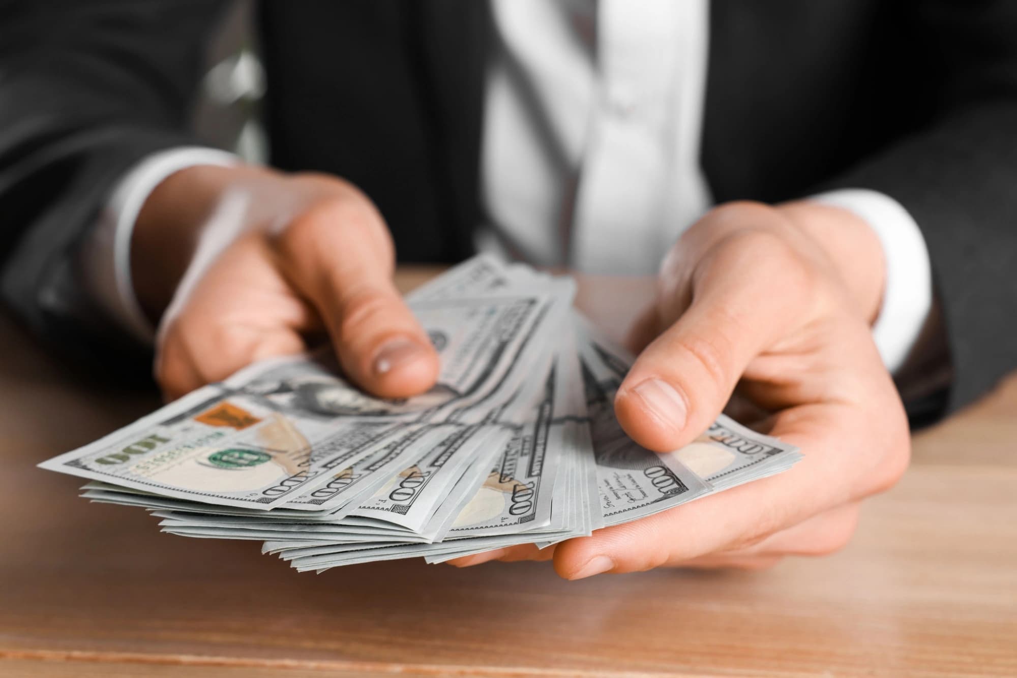 Man counting out one hundred dollar bills to pay his taxes