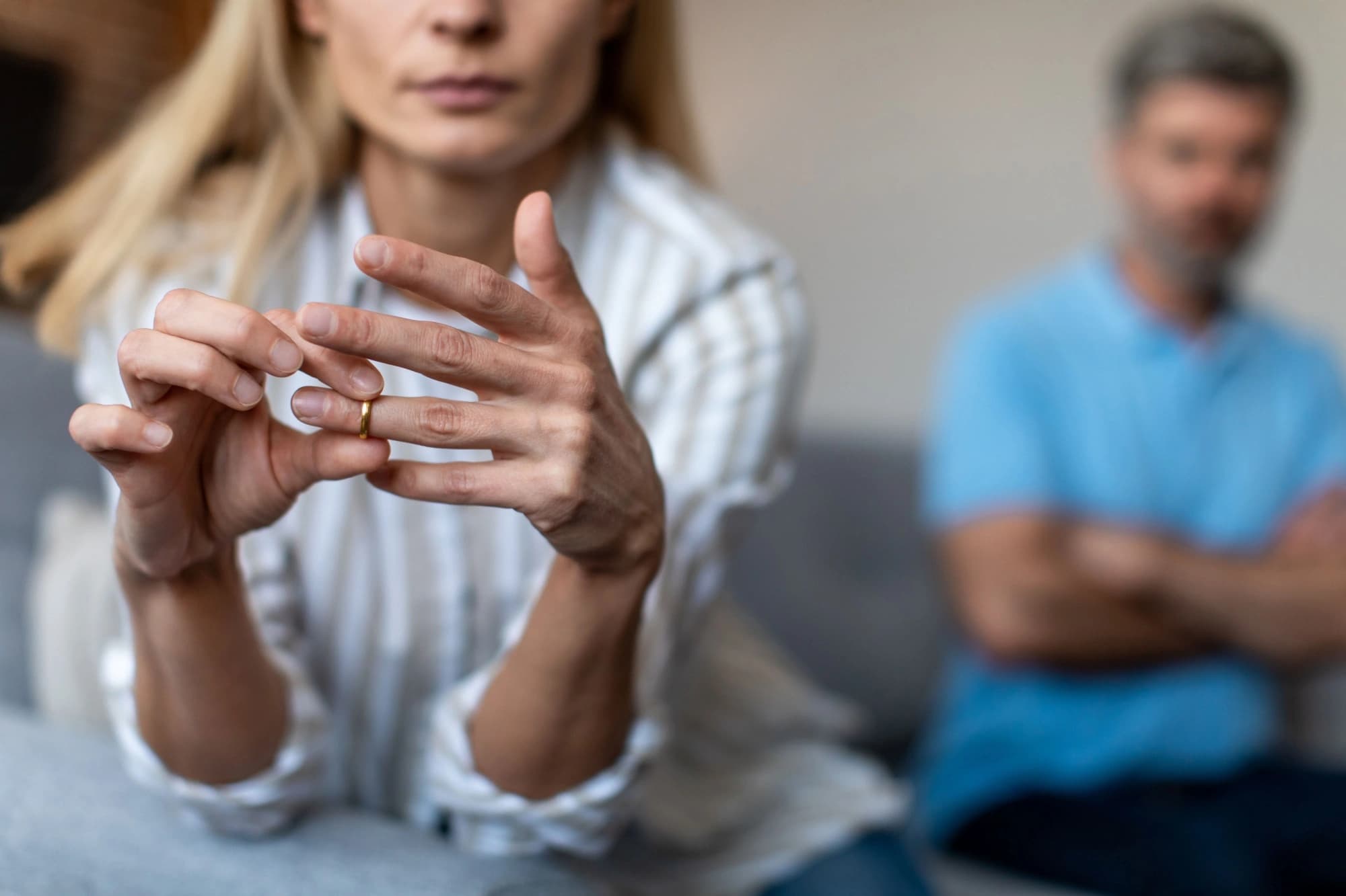 Close-up shot of a woman taking off her gold wedding band.