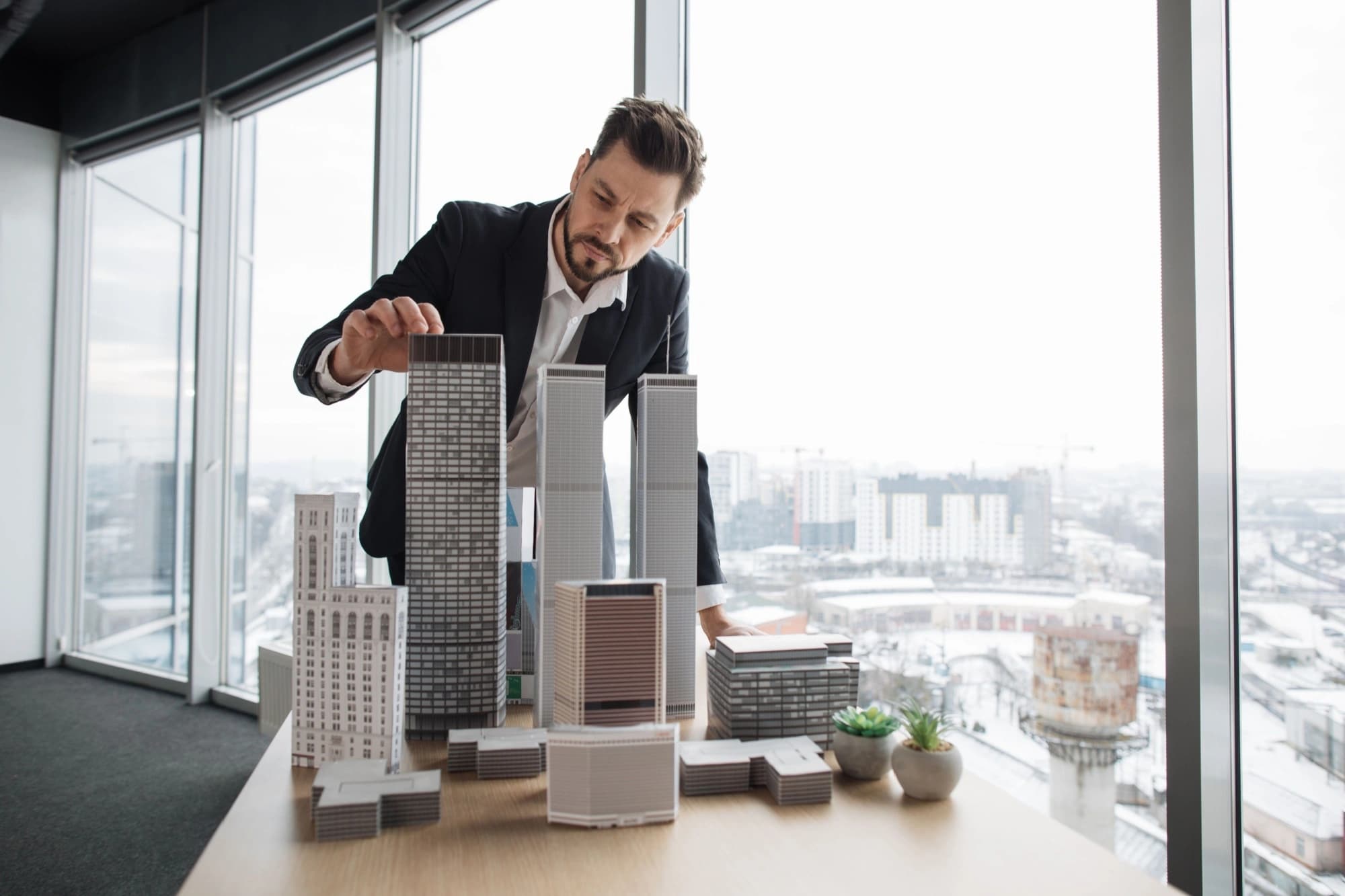 Wealthy real estate investor looking at a model of his building investment