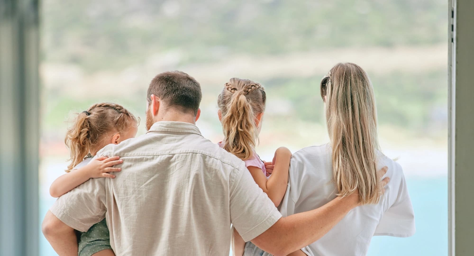 Family of four hugging while looking out the window