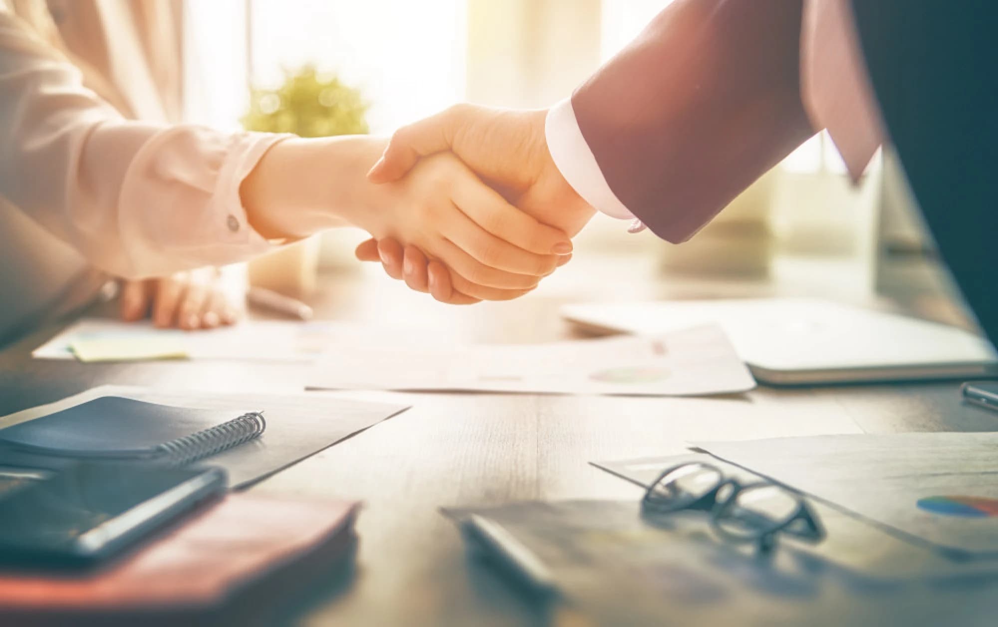 businesspeople shaking hands over a contract representing the sale of a business
