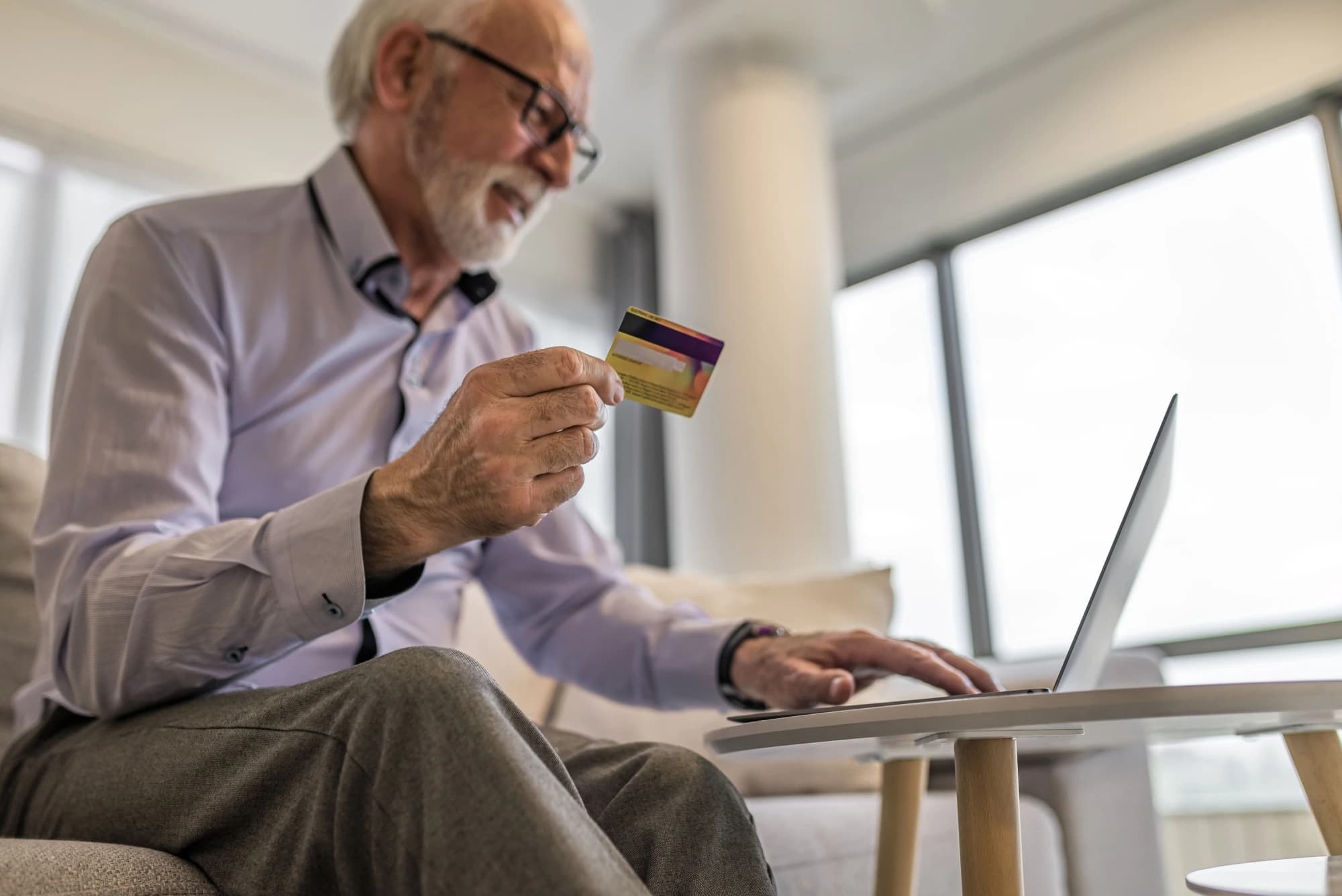 Retired man using his retirement spending to buy something on his laptop