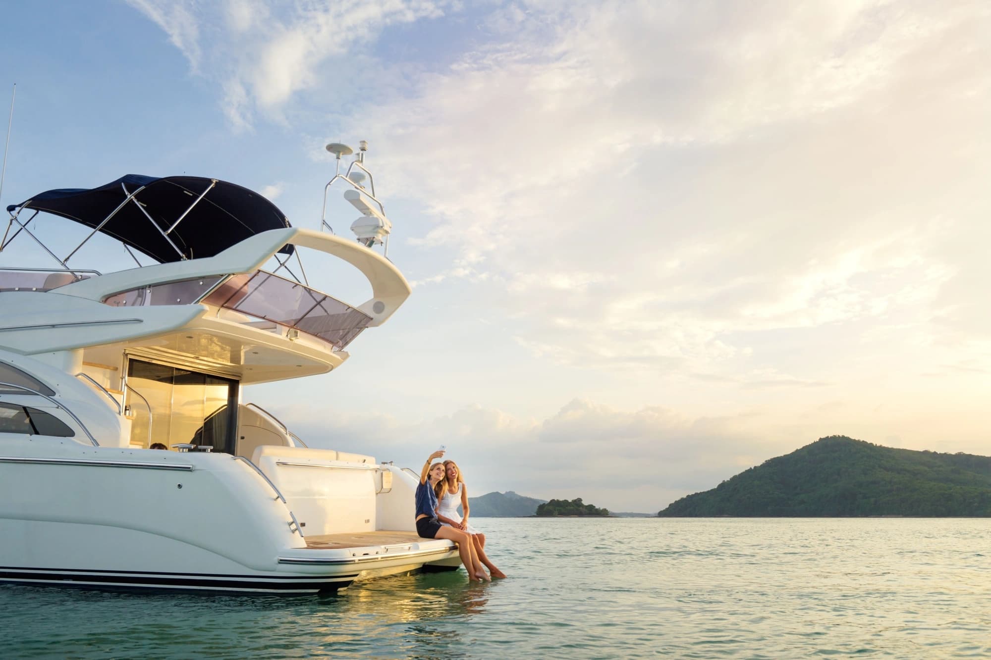 Two young women sitting on the back of a yacht