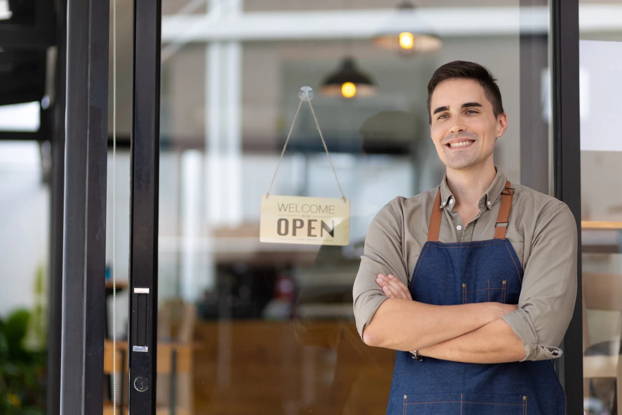 an entrepreneur standing in front of his business with an open sign in the door